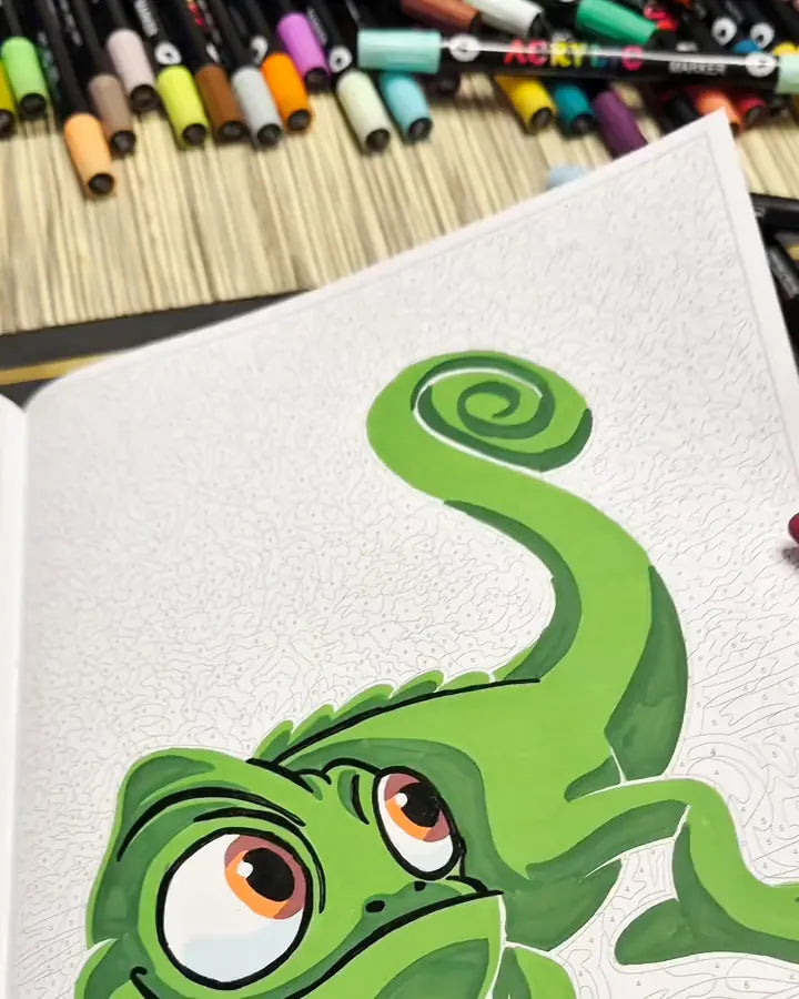 Coloriage d'un caméléon vert avec des feutres disposés au-dessus du carnet